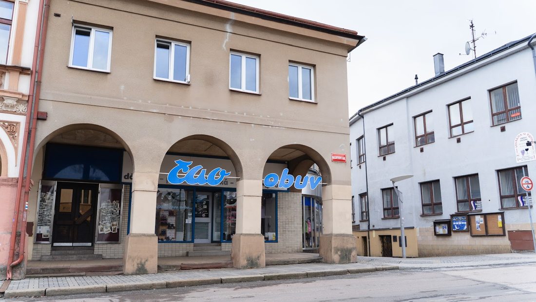 Dům na náměstí s podloubím a modrým nápisem Čao obuv nad výlohami